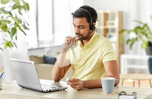 Image of indian man with headset and laptop working at home