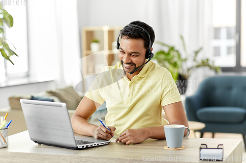 Image of indian man with headset and laptop working at home