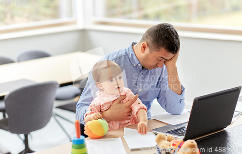 Image of father with baby working on laptop at home office