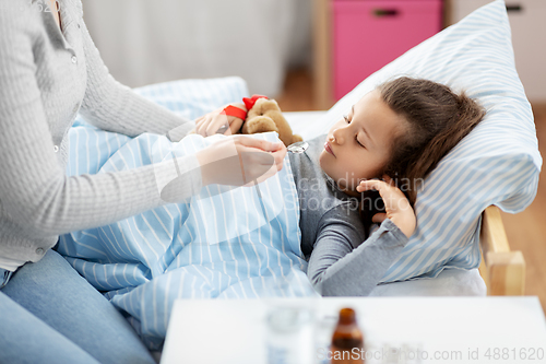 Image of mother giving cough syrup to sick daughter