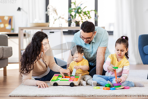 Image of happy family palying with wooden toys at home