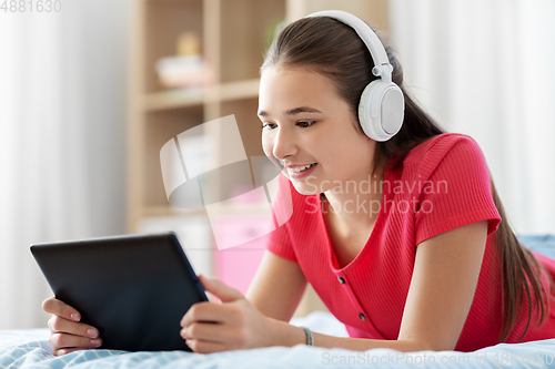 Image of girl in headphones listening to music on tablet pc