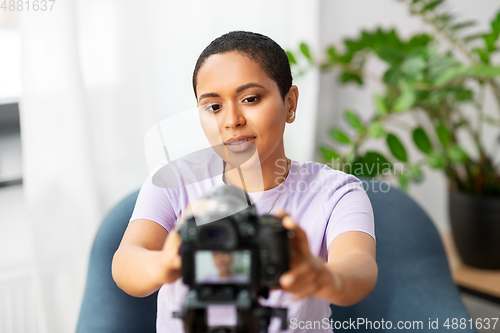 Image of female video blogger adjusting camera at home