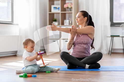 Image of happy mother with little baby exercising at home