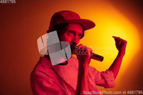 Image of Young caucasian musician playing, singing on gradient background in neon light. Concept of music, hobby, festival