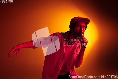 Image of Young caucasian musician playing, singing on gradient background in neon light. Concept of music, hobby, festival