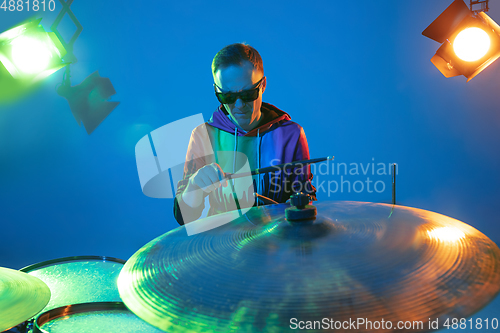 Image of Young caucasian musician playing on gradient background in neon light. Concept of music, hobby, festival