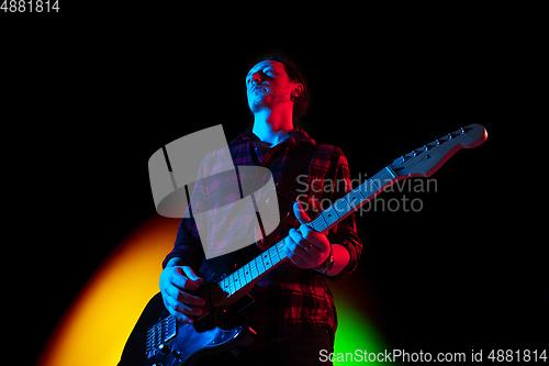 Image of Young caucasian musician playing on gradient background in neon light. Concept of music, hobby, festival