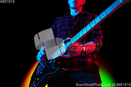 Image of Young caucasian musician playing on gradient background in neon light. Concept of music, hobby, festival