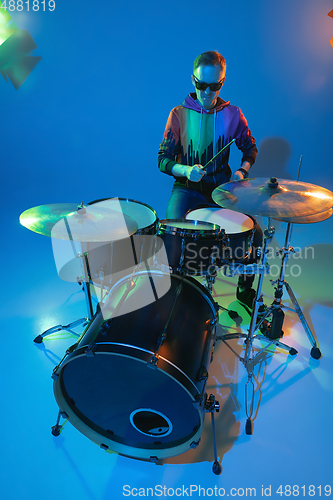 Image of Young caucasian musician playing on gradient background in neon light. Concept of music, hobby, festival