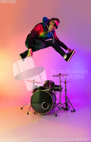 Image of Young caucasian musician playing on gradient background in neon light. Concept of music, hobby, festival