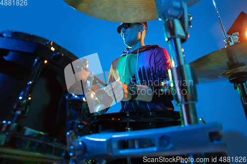 Image of Young caucasian musician playing on gradient background in neon light. Concept of music, hobby, festival