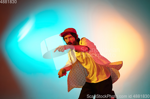 Image of Young caucasian musician playing, singing on gradient background in neon light. Concept of music, hobby, festival