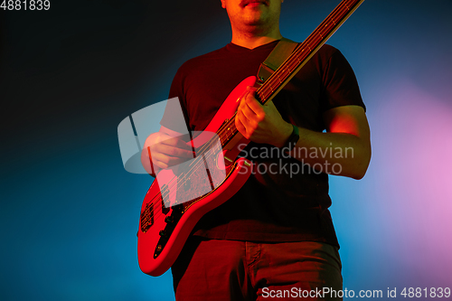 Image of Young caucasian musician playing on gradient background in neon light. Concept of music, hobby, festival