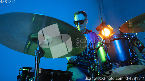 Image of Young caucasian musician playing on gradient background in neon light. Concept of music, hobby, festival