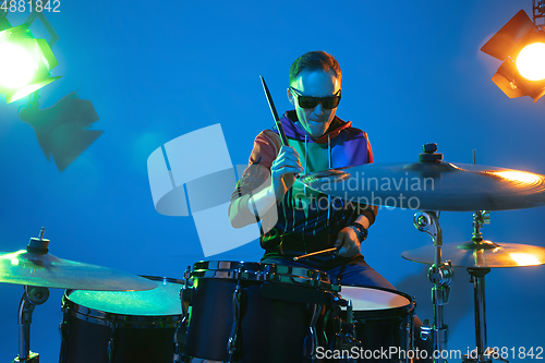 Image of Young caucasian musician playing on gradient background in neon light. Concept of music, hobby, festival