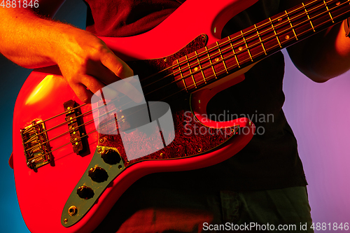 Image of Young caucasian musician playing on gradient background in neon light. Concept of music, hobby, festival