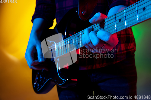 Image of Young caucasian musician playing on gradient background in neon light. Concept of music, hobby, festival