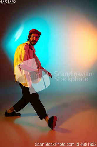 Image of Young caucasian musician playing, singing on gradient background in neon light. Concept of music, hobby, festival