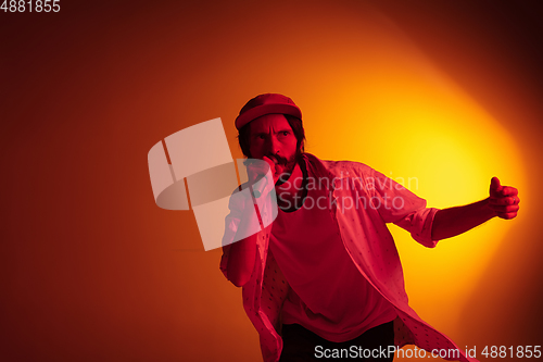 Image of Young caucasian musician playing, singing on gradient background in neon light. Concept of music, hobby, festival