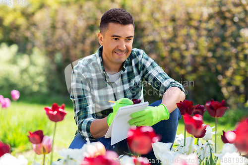 Image of man with notebook and flowers at summer garden