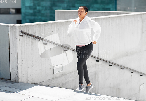 Image of african american woman running upstairs outdoors