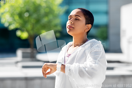 Image of young woman with smart watch breathing outdoors