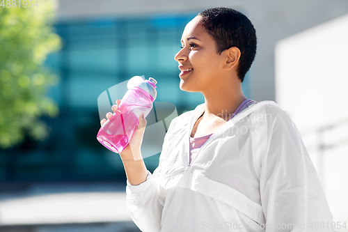 Image of african american woman drinking water from bottle