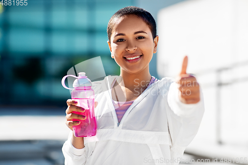 Image of happy woman with bottle of water showing thumbs up