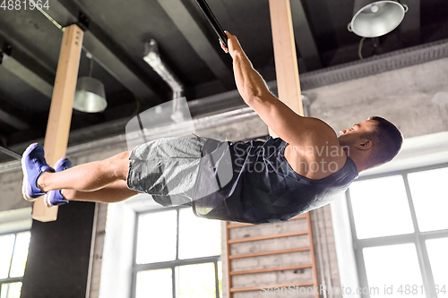 Image of young man exercising on horizontal bar in gym