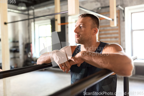 Image of young man at parallel bars in gym