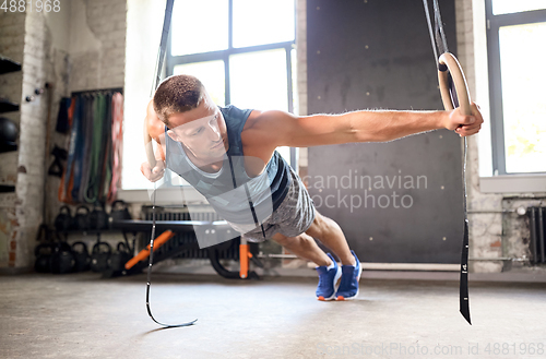 Image of man doing exercising on gymnastic rings in gym