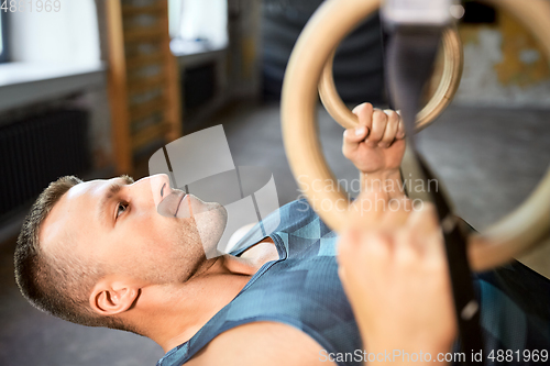 Image of man doing exercising on gymnastic rings in gym