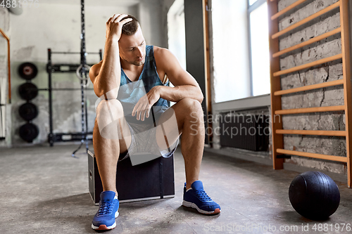 Image of tired young man with medicine ball in gym