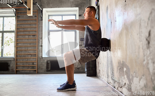 Image of young man exercising with medicine ball in gym