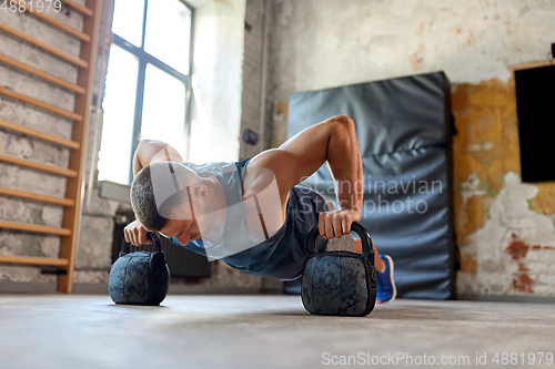 Image of young man doing kettlebell push-ups in gym