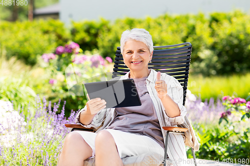 Image of happy senior woman with tablet pc at summer garden