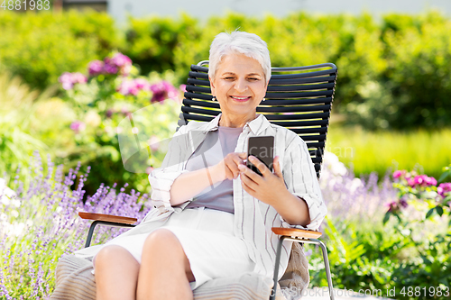 Image of happy senior woman with phone at summer garden