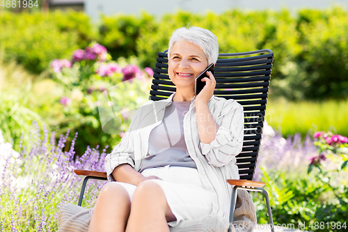 Image of happy senior woman calling on phone at garden