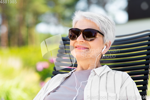 Image of happy senior woman with earphones at garden