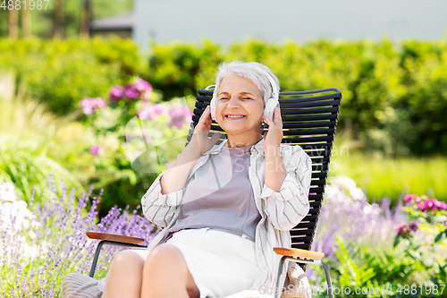 Image of happy senior woman with headphones at garden