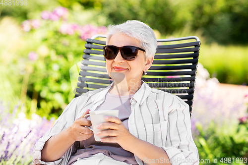 Image of happy senior woman drinking coffee at garden
