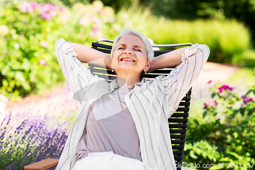 Image of happy senior woman resting at summer garden