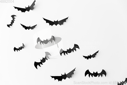 Image of flock of black paper bats over white background