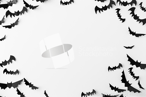 Image of flock of black paper bats over white background