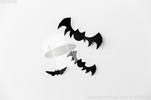 Image of flock of black paper bats over white background