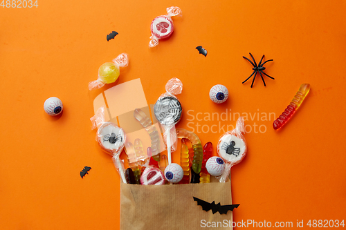 Image of halloween sweets in paper bag on orange background