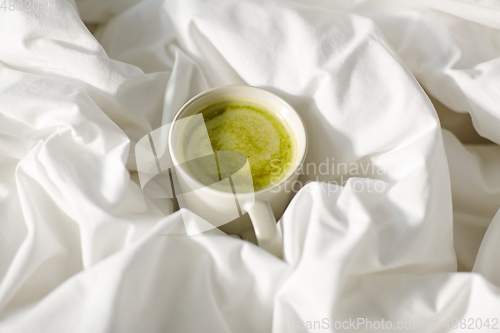 Image of cup of matcha tea in bed at home