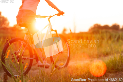 Image of Joyful young woman riding a bicycle at the riverside and meadow promenade