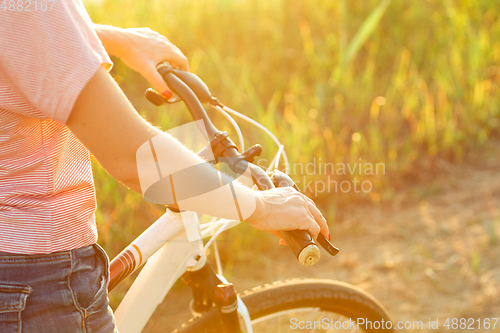 Image of Joyful young woman riding a bicycle at the riverside and meadow promenade